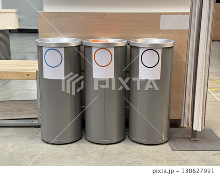 Three recycling bins with colored circle labels placed indoors. Waste management, environmental awareness and sustainability practice with cleanliness, organization and ecological responsibility. Three recycling bins with colored circle labels placed indoors. Waste management, environmental awareness and sustainability practice with cleanliness, organization and ecological responsibility. 130627991
