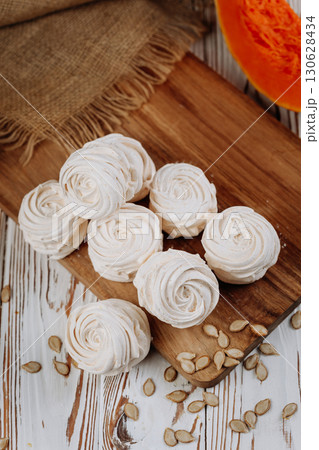 Homemade pumpkin marshmallows on rustic wooden table with seeds and autumn decor 130628434