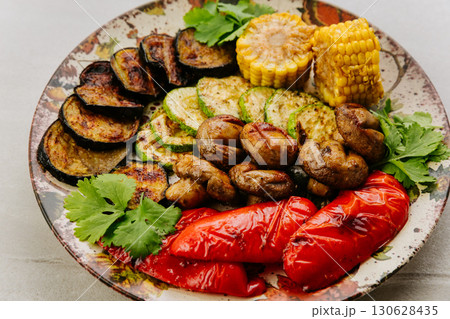 Grilled vegetables with herbs on ceramic plate. Colorful healthy vegan meal top view Grilled vegetables with herbs on ceramic plate. Colorful healthy vegan meal top view 130628435