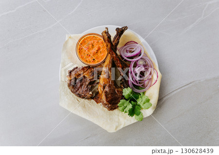 Grilled pork kebab with fresh herbs, red onion, lavash and spicy red pepper sauce 130628439