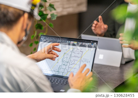 工事工程表を説明する男性主任技術者　ネットワーク工程表　工事監理　ヘルメット　2人 130628455