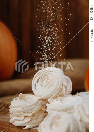 Pumpkin marshmallow sweets with powdered sugar falling, rustic autumn wooden background Pumpkin marshmallow sweets with powdered sugar falling, rustic autumn wooden background 130628469