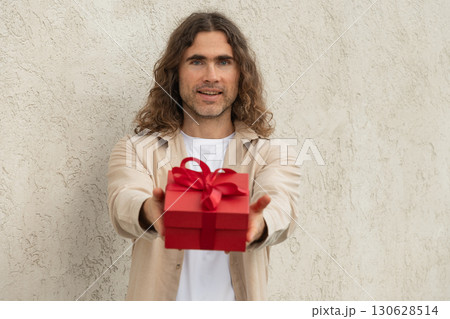 Happy handsome caucasian man giving red gift box with love. Birthday. Romantic surprise and celebration. Greeting card. 130628514