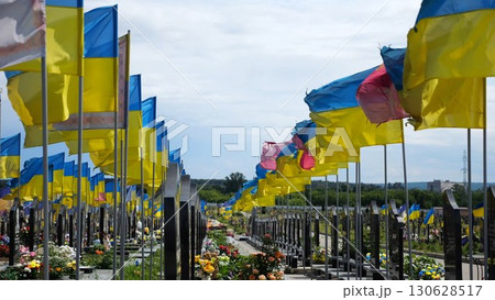 View on countless graves of ukrainian soldiers alley of glory in Kharkiv decorated with waving blue-yellow flags. The site commemorates soldiers who died during russian invasion in Ukraine. Slow mo 130628517