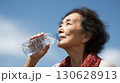 青空の下で水を飲む高齢女性のポートレート 130628913