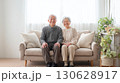 リビングのソファに座る笑顔の老夫婦 130628917