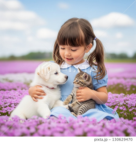 満開のピンクの芝桜畑で子犬と子猫を抱き、微笑むかわいい女の子のポートレート　 130629470