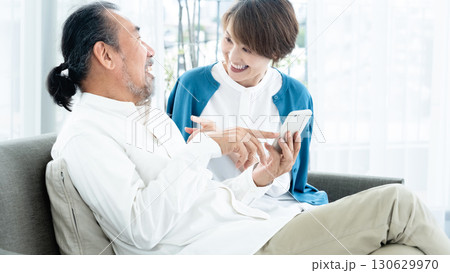 ソファでスマホを見るシニア夫婦 ソファでスマホを見るシニア夫婦 130629970
