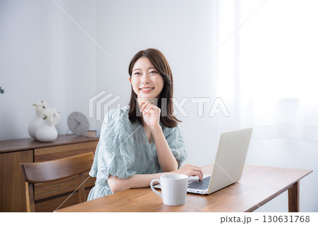 自宅の部屋でパソコンを使う若いかわいいカジュアルな服の女性カメラ目線 自宅の部屋でパソコンを使う若いかわいいカジュアルな服の女性カメラ目線 130631768