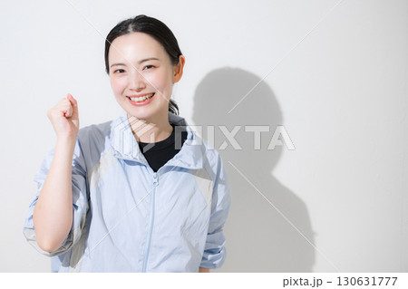 スポーツウェアで応援するガッツポーズの女性　カメラ目線笑顔 ダイエットなど運動頑張るぞ～！	 130631777