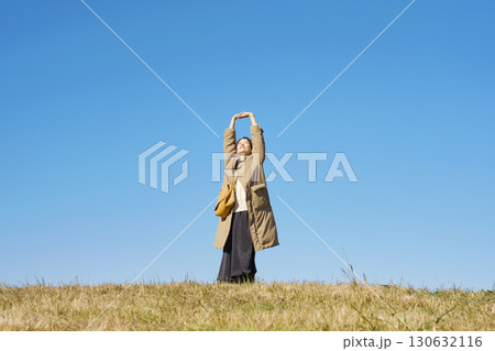 女性 ミドルエイジ 伸び 青空 全身 女性 ミドルエイジ 伸び 青空 全身 130632116