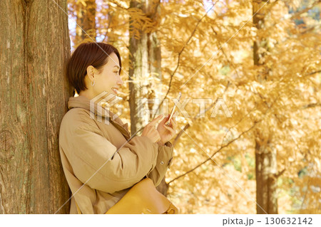 紅葉の中でスマホを使う女性　ミドルエイジ 130632142