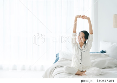 起きてストレッチをするパジャマの女性 130637364