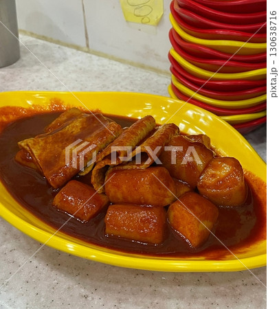 Spicy Korean tteokbokki with chewy rice cakes in a vibrant red sauce, topped with sesame seeds and green onions. A popular street food known for its addictive flavor and satisfying texture. 130638716
