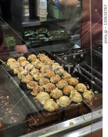 Takoyaki, a popular Japanese street food, are crispy round dough balls filled with octopus, tempura bits, and pickled ginger, topped with takoyaki sauce, bonito flakes, and aonori. Takoyaki, a popular Japanese street food, are crispy round dough balls filled with octopus, tempura bits, and pickled ginger, topped with takoyaki sauce, bonito flakes, and aonori. 130638767
