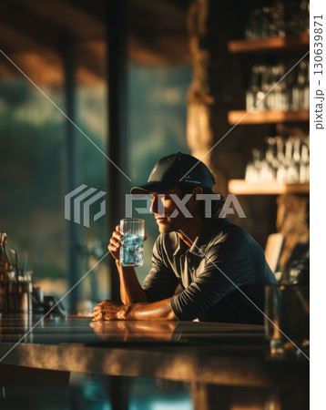 Man Enjoying Refreshing Drink in Modern Bar During Golden Hour Light 130639871