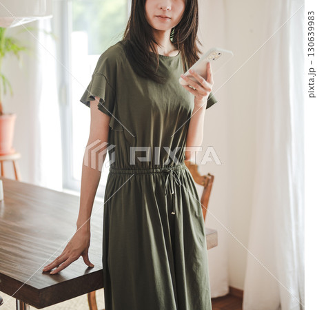 　ワンピース姿の女性とスマホ 130639983