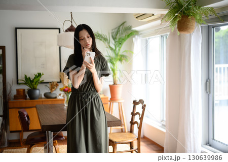 　ダイニングで微笑む女性とスマホ 130639986