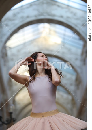 Ballet dancer posing gracefully under stone arch 130640629