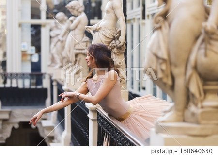 Ballet dancer leaning near statues in gallery 130640630