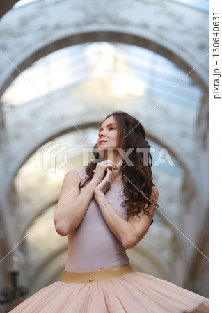 Ballet dancer in graceful pose under stone arch 130640631