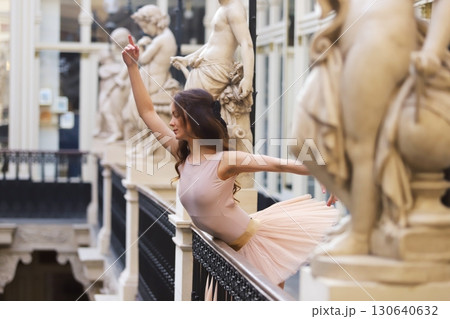 Ballet dancer posing gracefully near stone statues 130640632