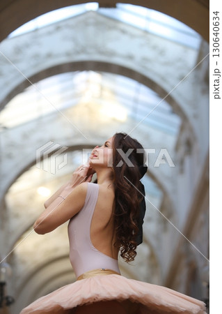 Ballet dancer in graceful pose under stone arch 130640634