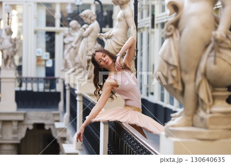 Ballet dancer posing gracefully near stone statues 130640635