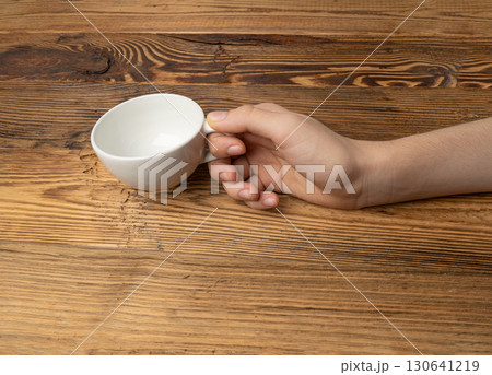 Hand Holds Cup, Empty White Cup in Hands, Coffee Mug, Teacup Mockup, Cup in Arms on Wooden Table Hand Holds Cup, Empty White Cup in Hands, Coffee Mug, Teacup Mockup, Cup in Arms on Wooden Table 130641219