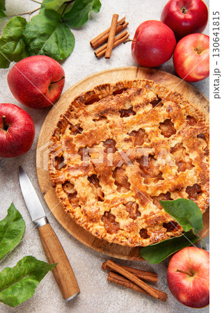Freshly baked apple pie decorated with cinnamon sticks and apple leaves on marble table 130641815