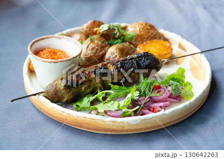 Georgian lula kebab plate. Bbq skewer, traditional barbecue dish with baked potatoes, sauce 130642263