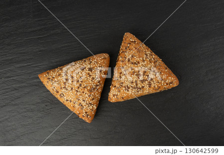 Triangular bun closeup. Wheat bread with sesame and flax seeds, healthy whole grain bakery 130642599