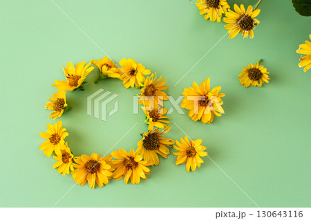 Blooming yellow flowers with natural leaves on green background 130643116