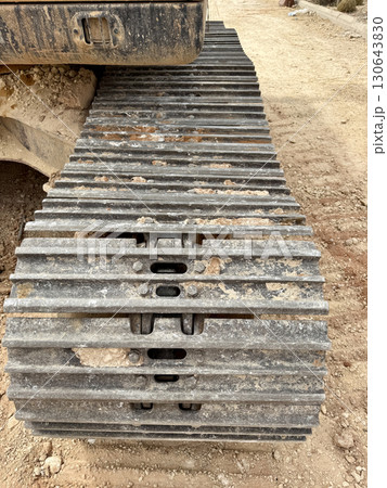 Complete metal excavator track on dirt ground, highlighted by rough texture and construction site dust, engineering, machinery, and industrial background concept Complete metal excavator track on dirt ground, highlighted by rough texture and construction site dust, engineering, machinery, and industrial background concept 130643830
