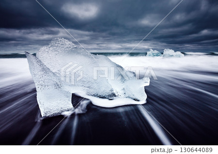 Ice fragments on black sand. Popular tourist attraction. Location Vatnajokull, Jokulsarlon lagoon, Iceland, Europe. 130644089