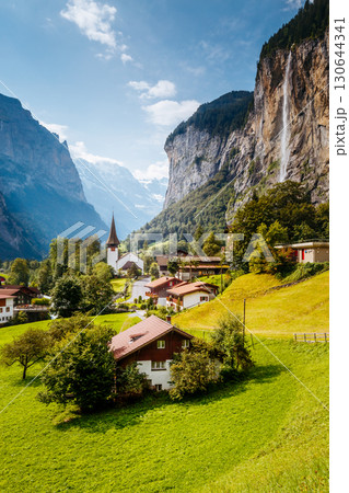 Great view of alpine village glowing by sunlight. Location Swiss alps, Lauterbrunnen valley, Staubbach waterfall, Europe. 130644341