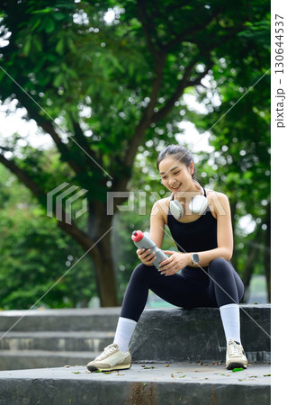 Fit female athlete with a water bottle and taking a break after exercise Fit female athlete with a water bottle and taking a break after exercise 130644537