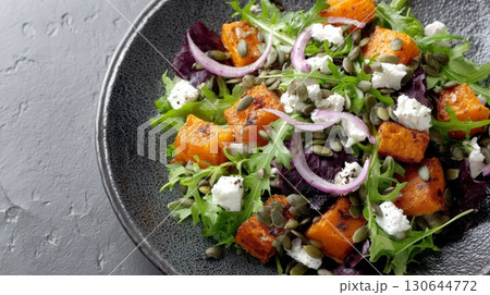 Fresh roasted pumpkin salad topped with greens, feta, and nutritious seeds arranged on a stylish plate Fresh roasted pumpkin salad topped with greens, feta, and nutritious seeds arranged on a stylish plate 130644772