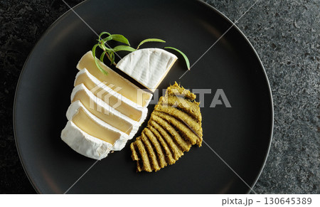 Camembert cream cheese with pesto on a black plate. 130645389