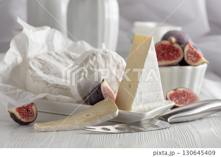 Camembert cheese with figs on a white table. 130645409