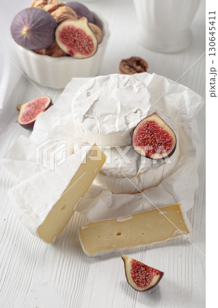 Camembert cheese with figs on a white table. 130645411