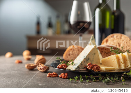 Cheese, bread, red wine, and walnuts on a kitchen table. 130645416