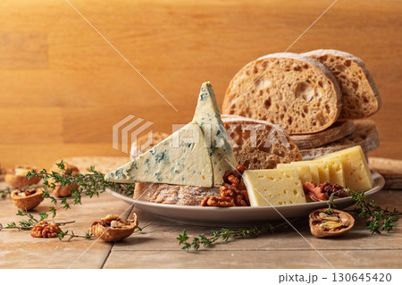Cheese, bread, walnuts, and thyme on a kitchen table. Cheese, bread, walnuts, and thyme on a kitchen table. 130645420