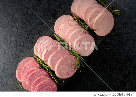 Various boiled sausages with rosemary on a black table. Various boiled sausages with rosemary on a black table. 130645448