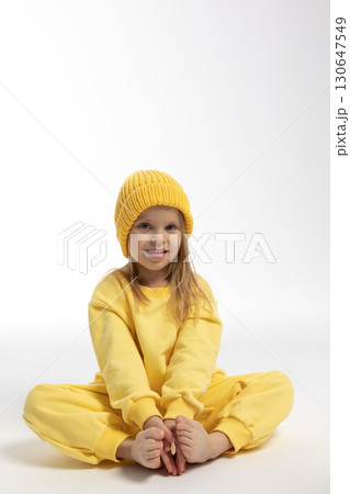Portrait of beautiful cute little toddler girl. Child with funny face in yellow sweatshirt and hat. Pretty smile kid in studio on white background. High quality photo 130647549