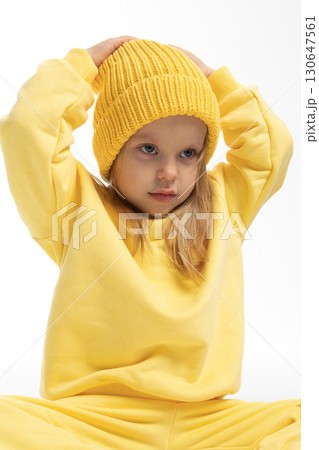 Portrait of beautiful cute little toddler girl. Child with funny face in yellow sweatshirt and hat. Pretty smile kid in studio on white background. High quality photo Portrait of beautiful cute little toddler girl. Child with funny face in yellow sweatshirt and hat. Pretty smile kid in studio on white background. High quality photo 130647561