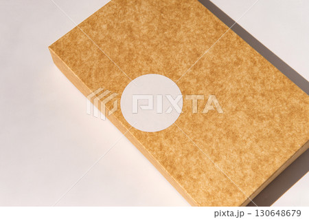 Brown textured cardboard box with circular white label on surface 130648679