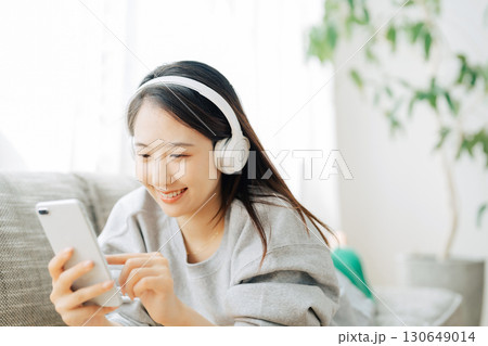 音楽を聴きながらスマホを見る女性 130649014