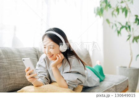 音楽を聴きながらスマホを見る女性 130649015
