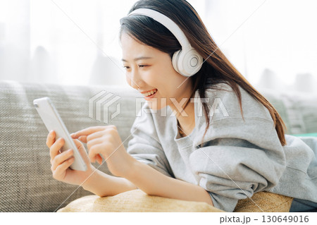 音楽を聴きながらスマホを見る女性 130649016